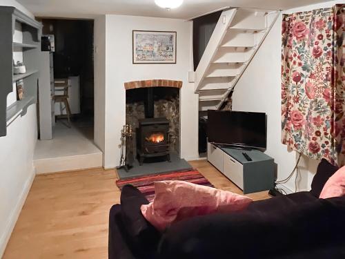 sala de estar con chimenea y sofá en Smithy End en Chard