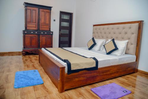 ein Schlafzimmer mit einem Holzbett, einem Holzschrank und blauen Matten in der Unterkunft Muthu villa in Ambalangoda