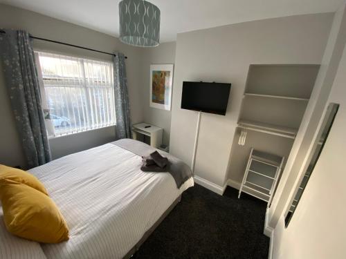 a small bedroom with a bed and a television at Connswater Town House Belfast in Belfast