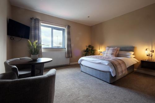a bedroom with a bed and a chair and a window at Bannview Bed & Breakfast in Portadown