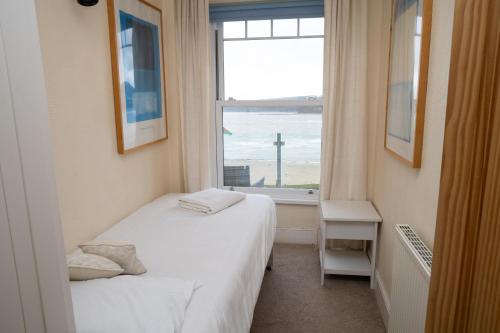 a bedroom with a bed and a window with the ocean at No. 1 Cliffside New Quay in New Quay