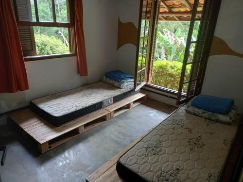 two beds in a room with two windows at Sitio Humanaterra: natureza e acolhimento. in São Lourenço da Serra