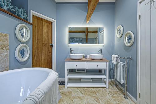 a blue bathroom with two sinks and a tub at Goferydd, South Stack, Anglesey, 4 bed luxury home, hot tub, dog friendly in Holyhead