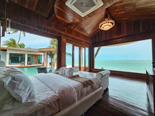 a bedroom with a bed and a view of the ocean at Hotel Villa AoKhanom Beachfront in Khanom