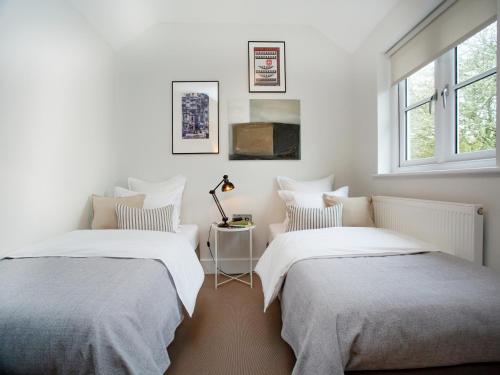 2 camas en una habitación con paredes y ventanas blancas en Myrtle House, en Pendeen