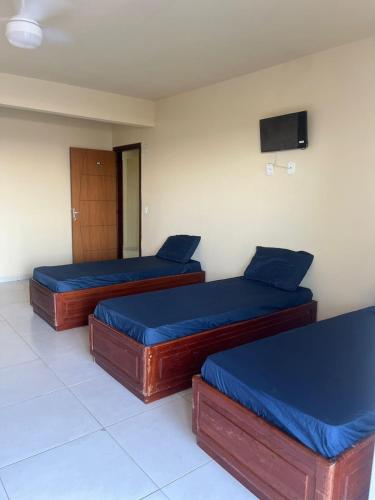 two beds in a room with a tv on the wall at Maria Flor Pousada e kitnet in São Mateus