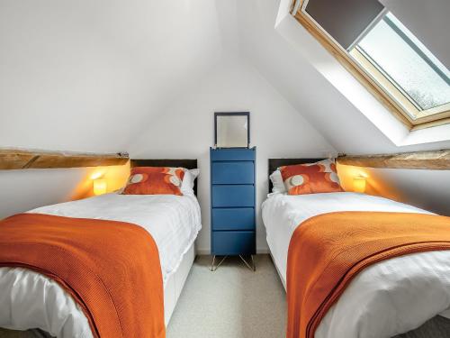 - une chambre mansardée avec 2 lits dotés de draps orange dans l'établissement Waveney Valley View, à Burgh Saint Peter