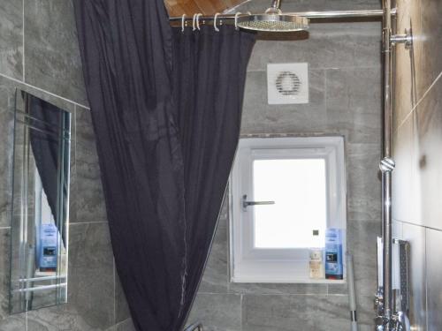 a shower with a black curtain in a bathroom at The Shepherds Hut - Uk46633 in Culbokie