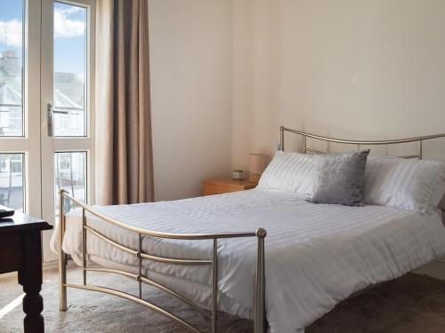 una camera da letto con un letto con lenzuola bianche e una finestra di Avondale a Clacton-on-Sea