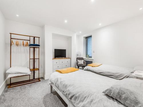 um quarto branco com 2 camas e uma televisão em Ethelbert Apartment em Westgate on Sea