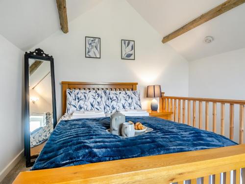 a bedroom with a large bed with a blue comforter at The Barn in Martham