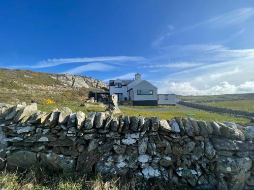 a stone wall in front of a white house at Goferydd, South Stack, Anglesey, 4 bed luxury home, hot tub, dog friendly in Holyhead