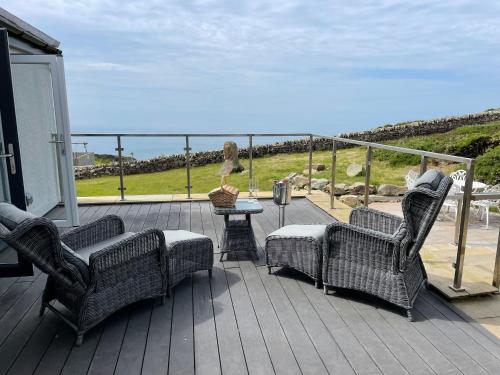 a deck with two chairs and a table with a view of the ocean at Goferydd, South Stack, Anglesey, 4 bed luxury home, hot tub, dog friendly in Holyhead