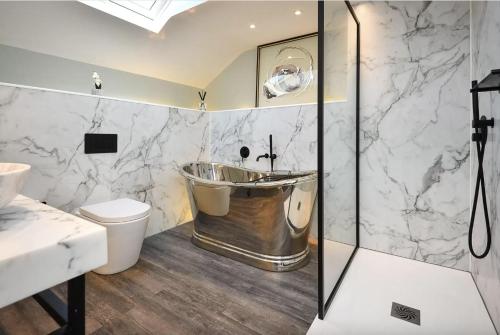a bathroom with a tub and a toilet and a sink at Goferydd, South Stack, Anglesey, 4 bed luxury home, hot tub, dog friendly in Holyhead