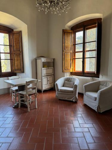 a living room with chairs and a table and windows at Castello Vicchiomaggio in Greve in Chianti