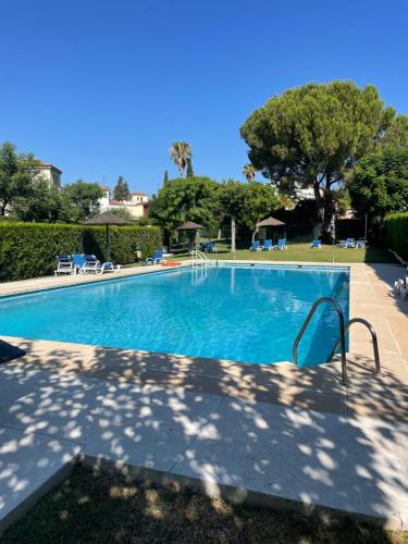 una piscina en un complejo con árboles y un cielo azul en Atuaire Apartment Sevilla, en Mairena del Aljarafe