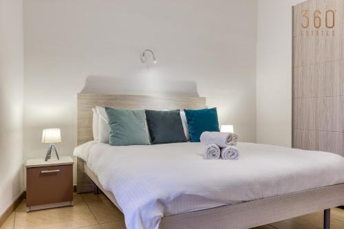 - une chambre avec un grand lit et des serviettes dans l'établissement A comfy 2BR home with Balcony Views in Kalkara by 360 Estates, à Kalkara