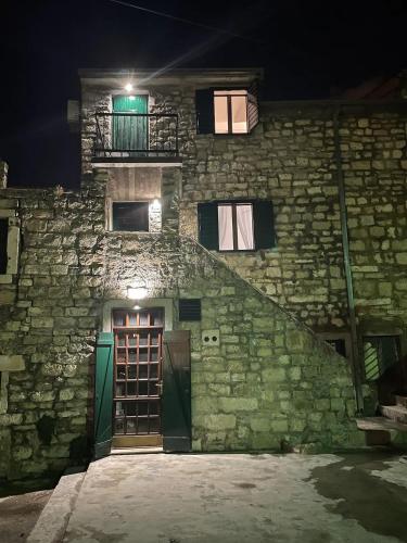 a stone building with a staircase and windows at night at Holiday Home Old Art in Kaštela