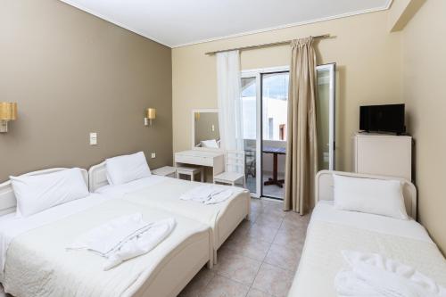 a bedroom with two beds and a balcony at Hotel Venetia in Perdhika