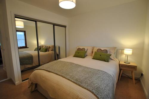 1 dormitorio con 1 cama grande y espejo en Meadowshores Apartment Crail, en Crail
