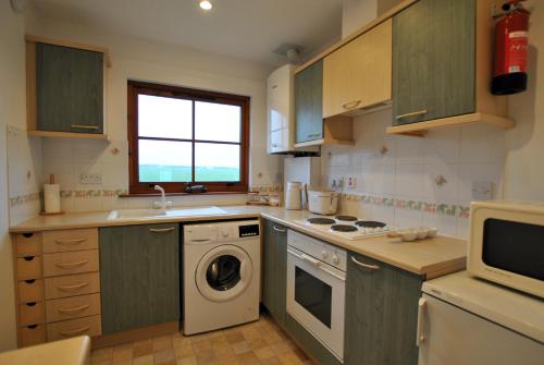 cocina con lavadora y microondas en Meadowshores Apartment Crail, en Crail