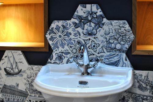 a white sink in a bathroom with a tile wall at The House on the Square- Coastal Townhouse in Saint Monance