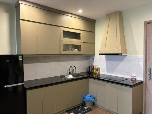 uma cozinha com armários brancos e bancadas pretas em Vung Homestay - 1+ Bedroom Apartment em Hanói