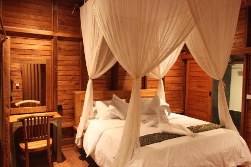 1 dormitorio con 1 cama con mosquitera en Manuk Dewata Villa, en Sidemen
