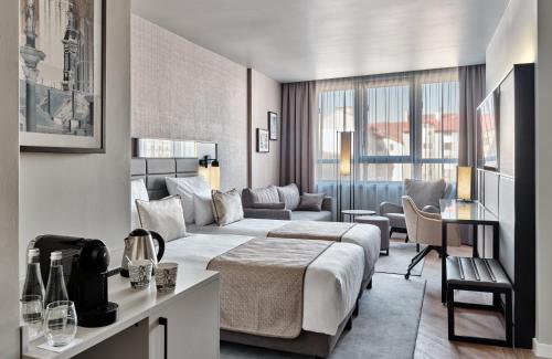 pokój hotelowy z łóżkiem i kanapą w obiekcie Leonardo Royal Hotel Warsaw w Warszawie