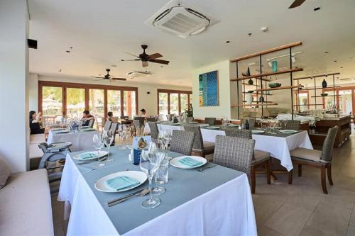 uma sala de jantar com mesas e cadeiras brancas em The Ocean Villa Đà Nẵng em Da Nang