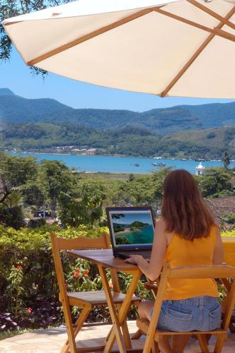 a woman sitting at a table with a laptop at Pousada Morro do Forte in Paraty