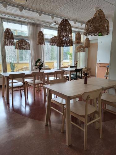 un comedor con mesas, sillas y ventanas en EnjoyNature B&B en Lahti