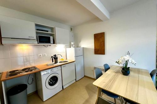 a kitchen with a table and a sink and a stove at Les Naïades G29 - 2 bedrooms for 5 people ! in Avène