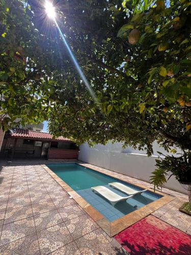 uma piscina debaixo de uma árvore ao lado de um edifício em Excelente quarto em Alphaville em Santana de Parnaíba