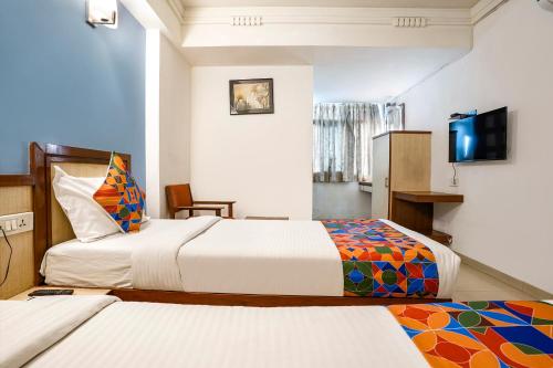 hotelshantisadan في أحمد آباد: غرفة فندقية بسريرين وتلفزيون بشاشة مسطحة