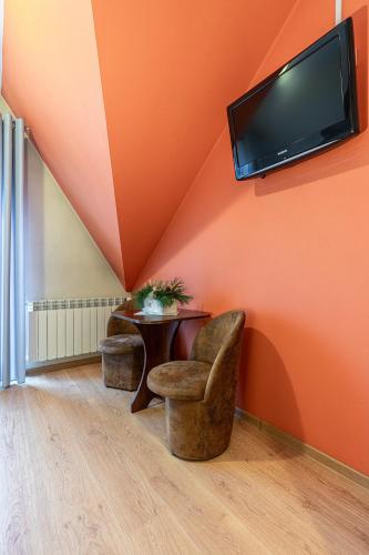 an orange room with a table and two chairs and a tv at Leśny Dworek Biały Dunajec in Zakopane