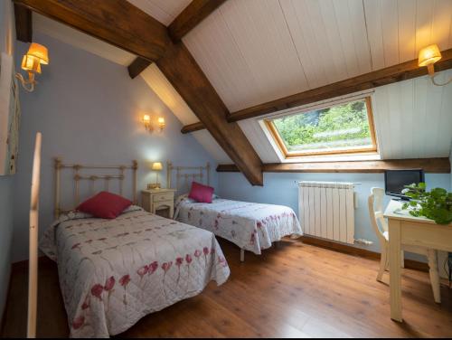 a attic room with two beds and a window at La Fuen hostal Bielsa-Parzan in Parzán