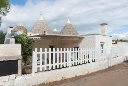 una recinzione bianca di fronte a una casa con torrette di Trullo da Nonno Marco a Cisternino