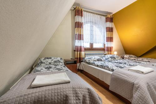 two beds in a room with a window at Leśny Dworek Biały Dunajec in Zakopane