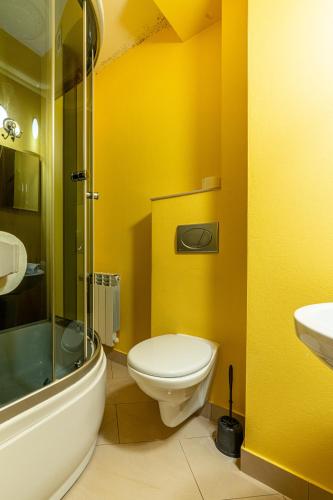 a yellow bathroom with a toilet and a shower at Leśny Dworek Biały Dunajec in Zakopane