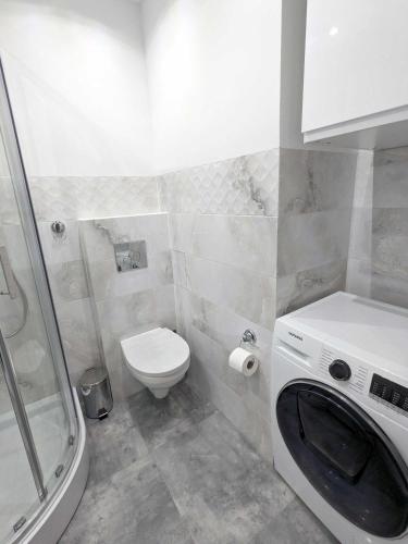 a bathroom with a toilet and a washing machine at Misia Casa - Ultra-Modern Spotless Apartment in Historic Torun in Toruń