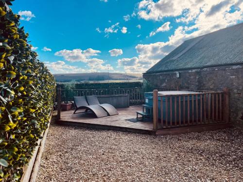 una terraza de madera con sofá y sillas. en The Bothy, en Kelso