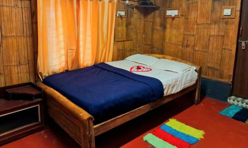 a small bed in a room with wooden walls at Livi Homestay in Ambalavayal
