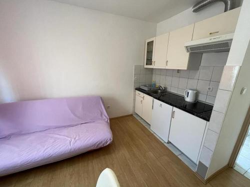 una pequeña cocina con una cama morada en una habitación en Apartments Lemon, en Vodice