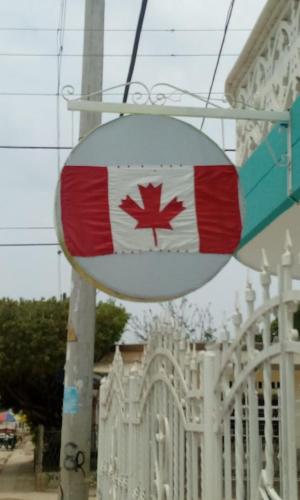 een bord met een Canadese vlag voor een hek bij Canadian House Tolú in Tolú