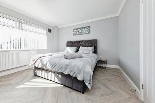 a white bedroom with a large bed and a window at Spacious 3 Bedroom Modern House with Garden in Kent