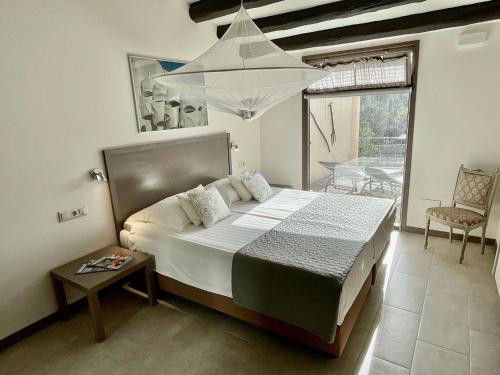 een slaapkamer met een bed, een tafel en een kroonluchter bij Bungalow Riu d'Agost with private terrace in La Torre de Claramunt
