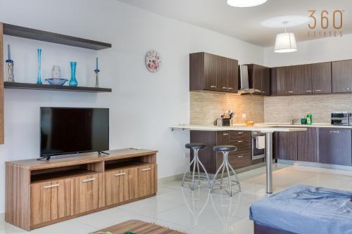 a kitchen with a television and a counter with stools at Beautiful PENT with terrace & spectacular views by 360 Estates in Luqa