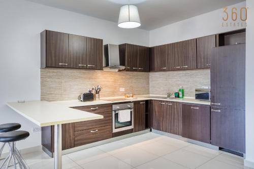 a kitchen with wooden cabinets and a white counter top at Beautiful PENT with terrace & spectacular views by 360 Estates in Luqa