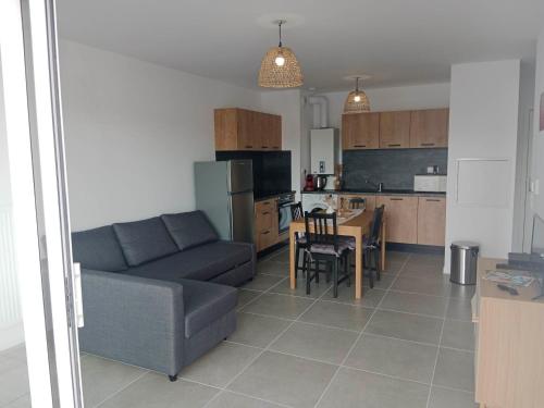 ein Wohnzimmer und eine Küche mit einem Sofa und einem Tisch in der Unterkunft APPARTEMENT 4 COUCHAGES in Soustons